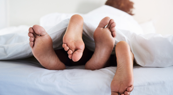 Deux paires de pieds dépassent du lit